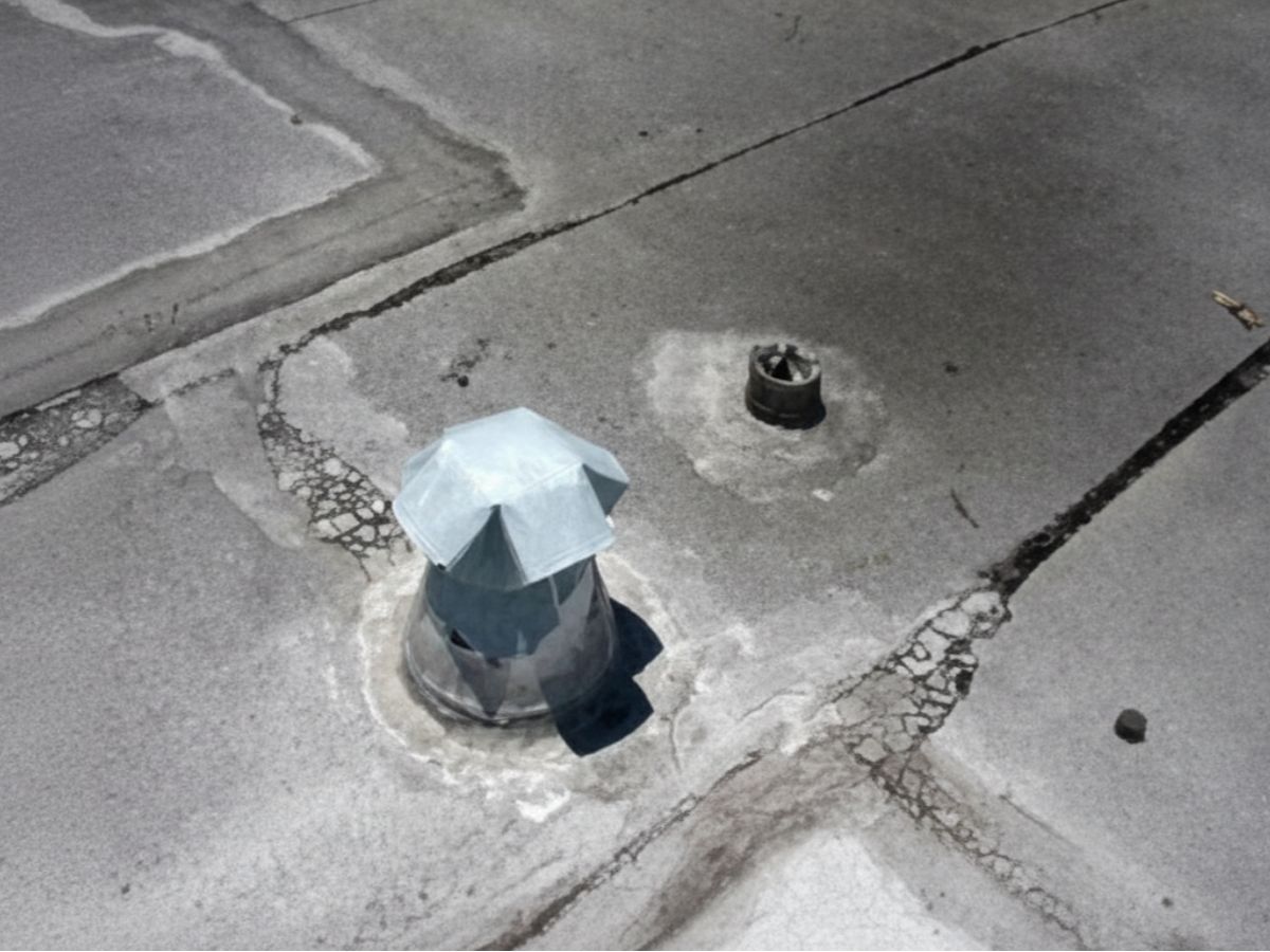 Flat roof surface with metal vent cap and roof penetration