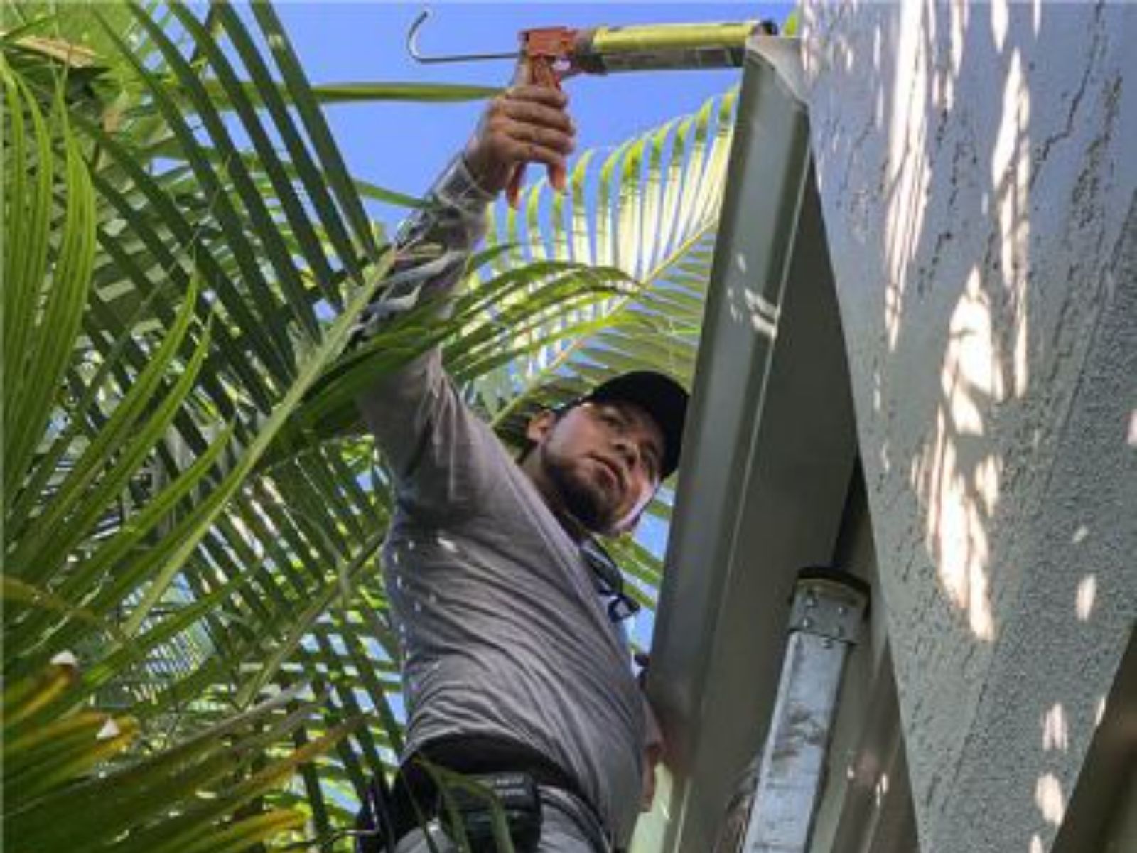 Professional gutter installer sealing an aluminum gutter joint on a residential home to prevent leaks and water damage