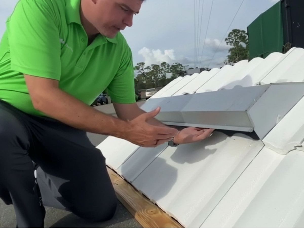 Technician inspecting metal roof flashing installation
