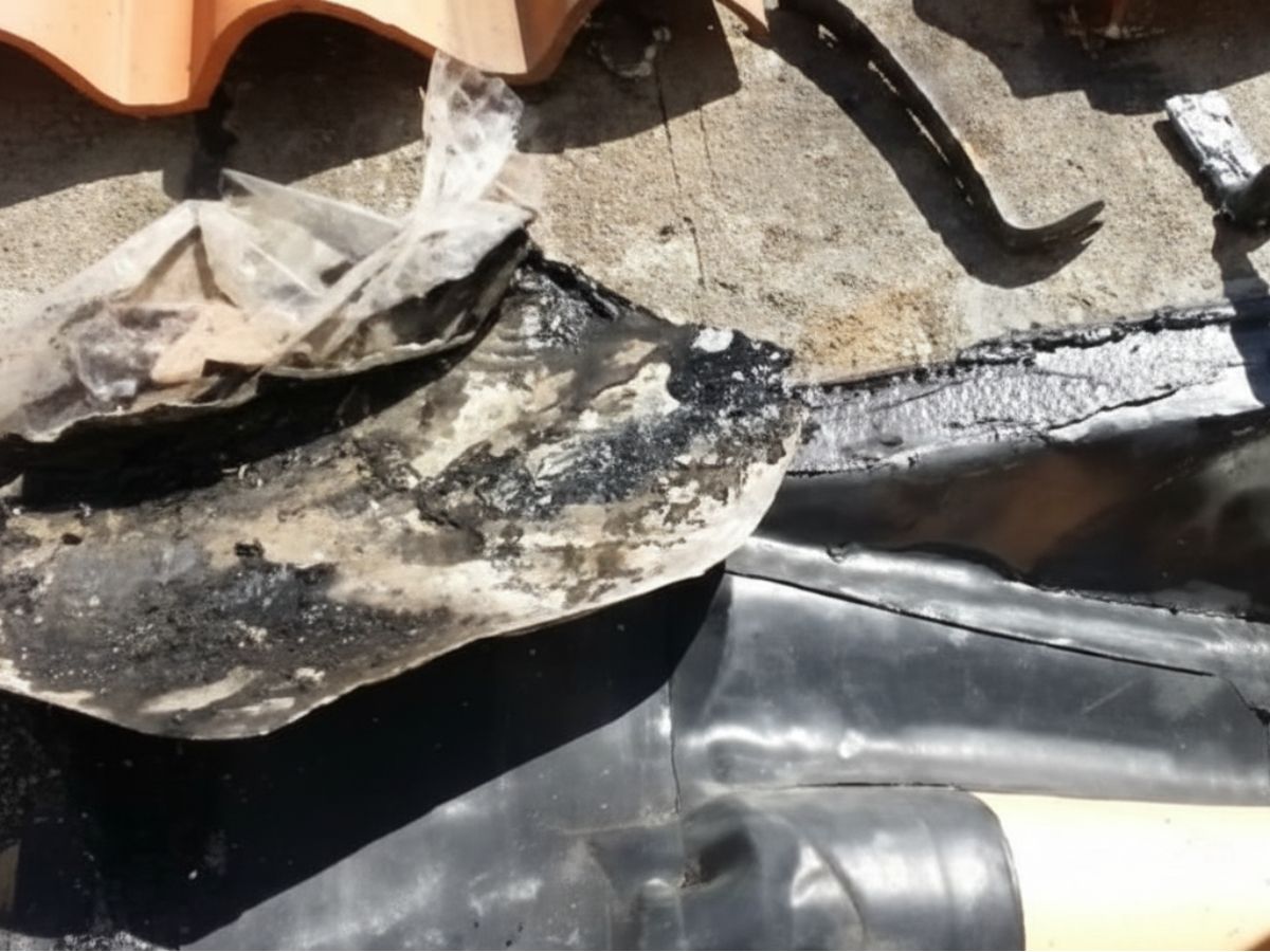 Severely deteriorated roof flashing and underlayment beneath tile roof causing active leak risk