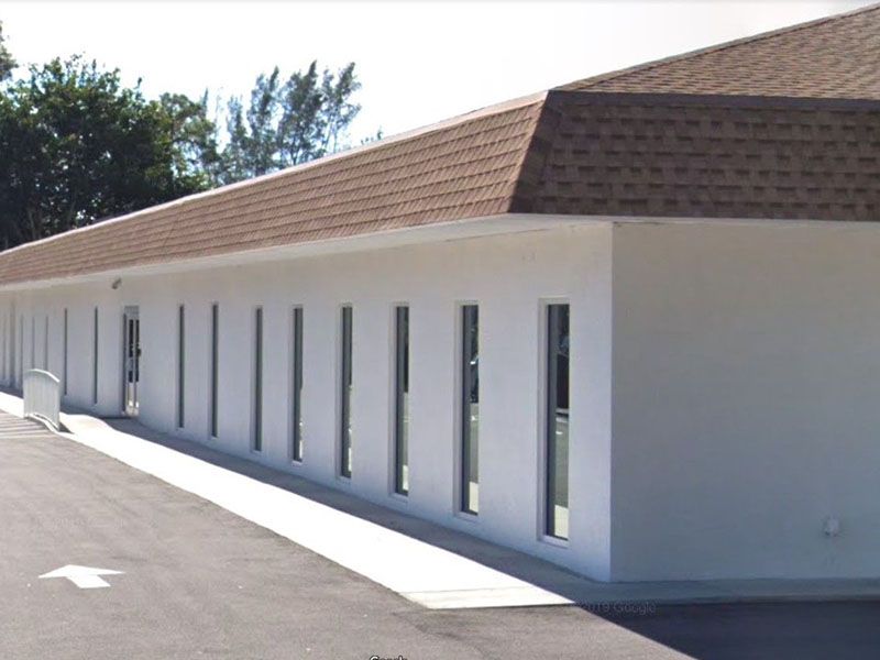 White concrete building, many narrow windows, with brown tile roof