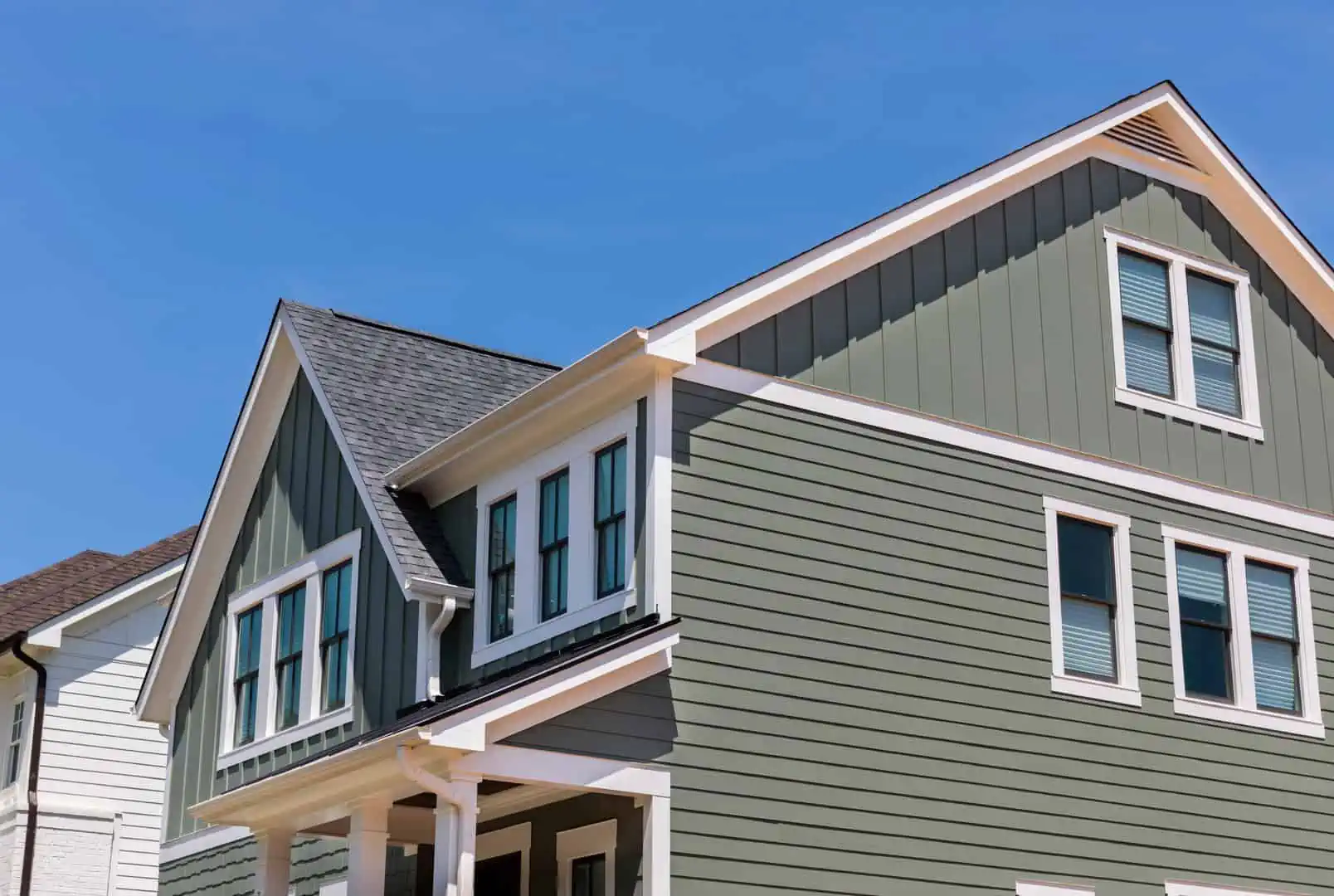 Green home with many windows and blue sky backdrop