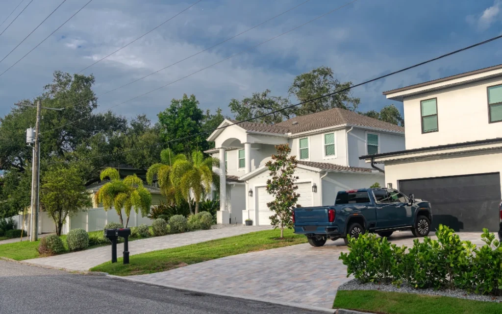 White two-story Florida home with tile roof under cloudy pre-storm skies in a residential neighborhood.