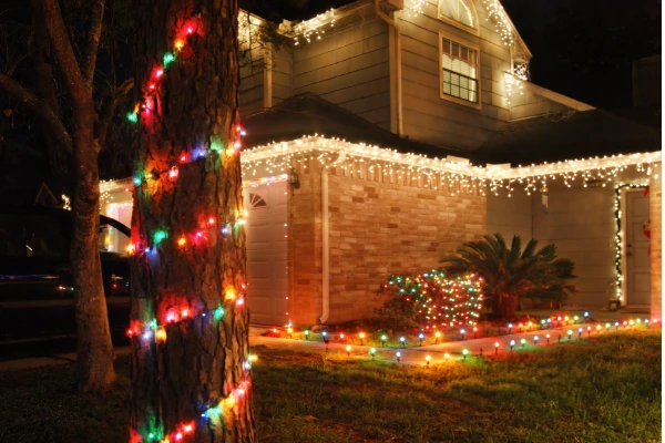 Home decorated with colorful holiday lights along the roofline and front yard