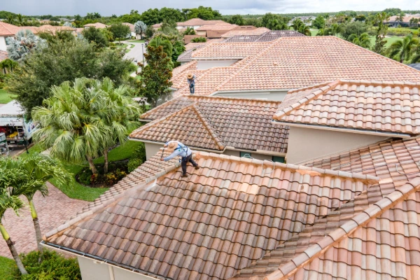 Roofing crew members cleaning a clay tile roof on a Florida home
